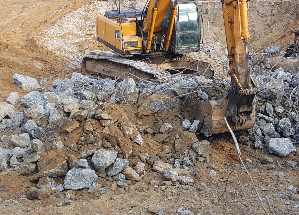 Excavator breaking up and removing concrete