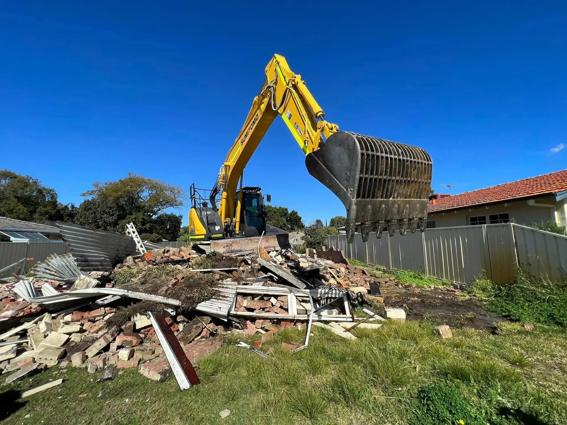 Excavator loading demolition debris from a house site