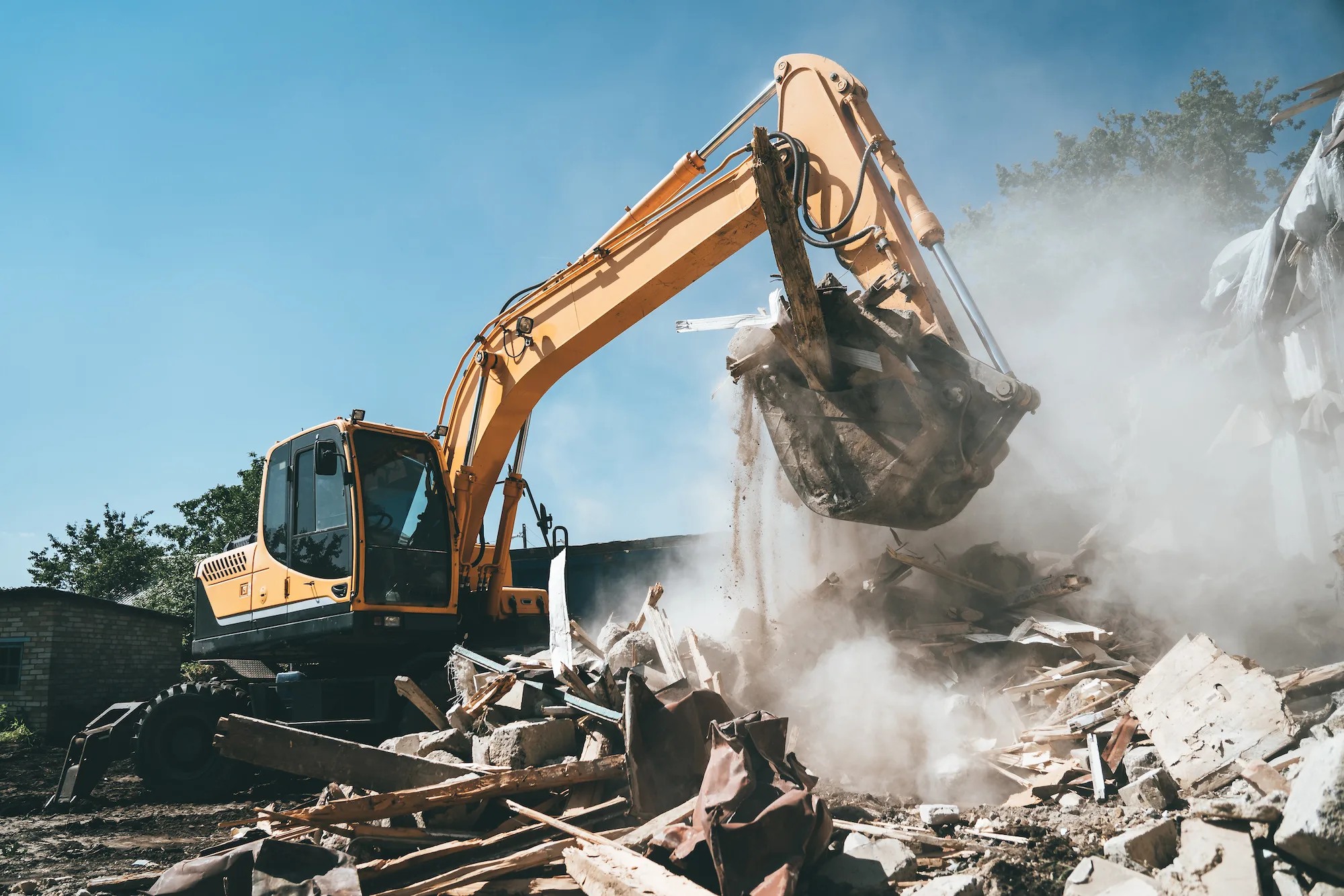 Excavator demolishing a building with dust suppression