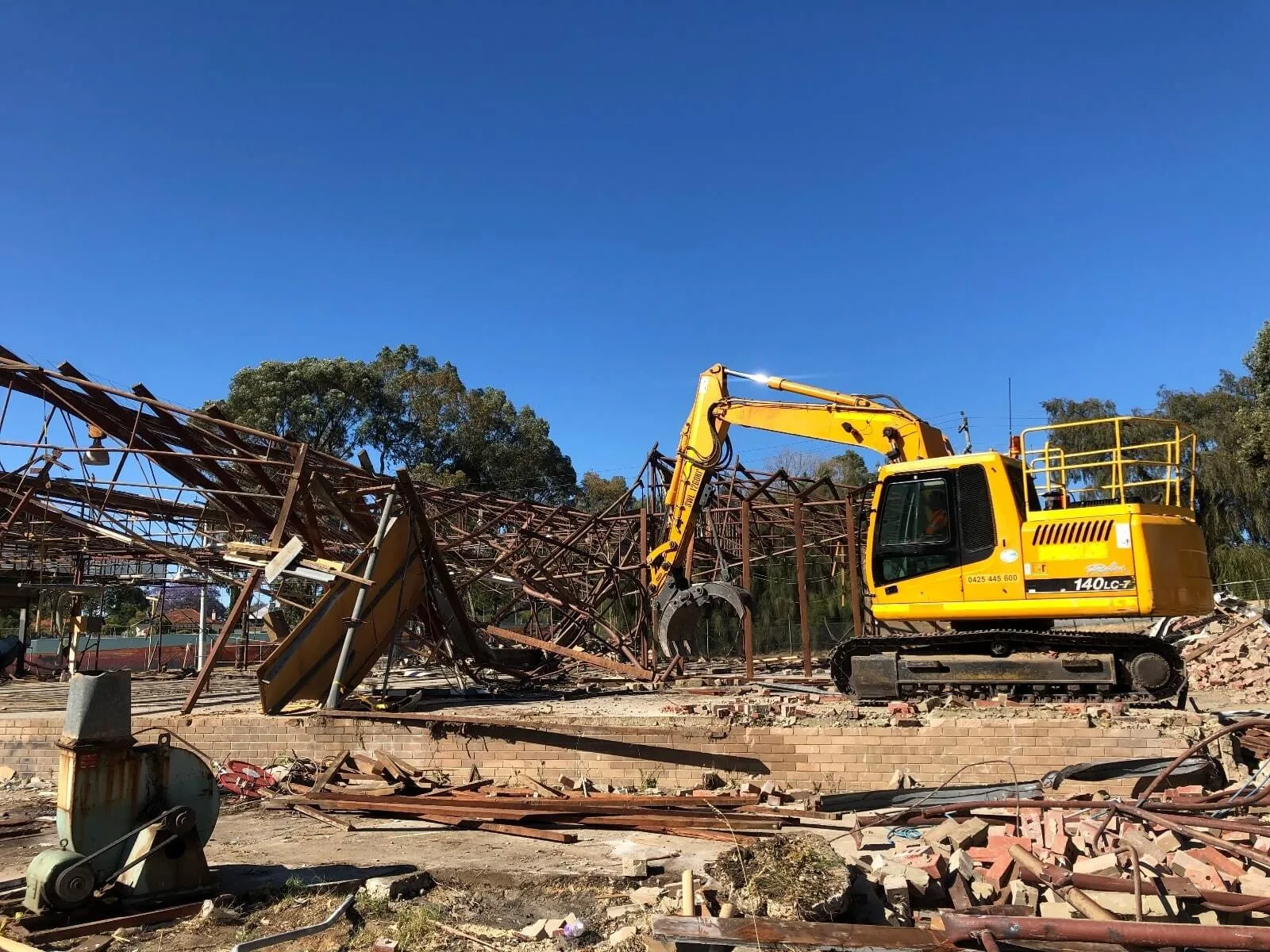 Excavator removing a collapsed steel-framed structure
