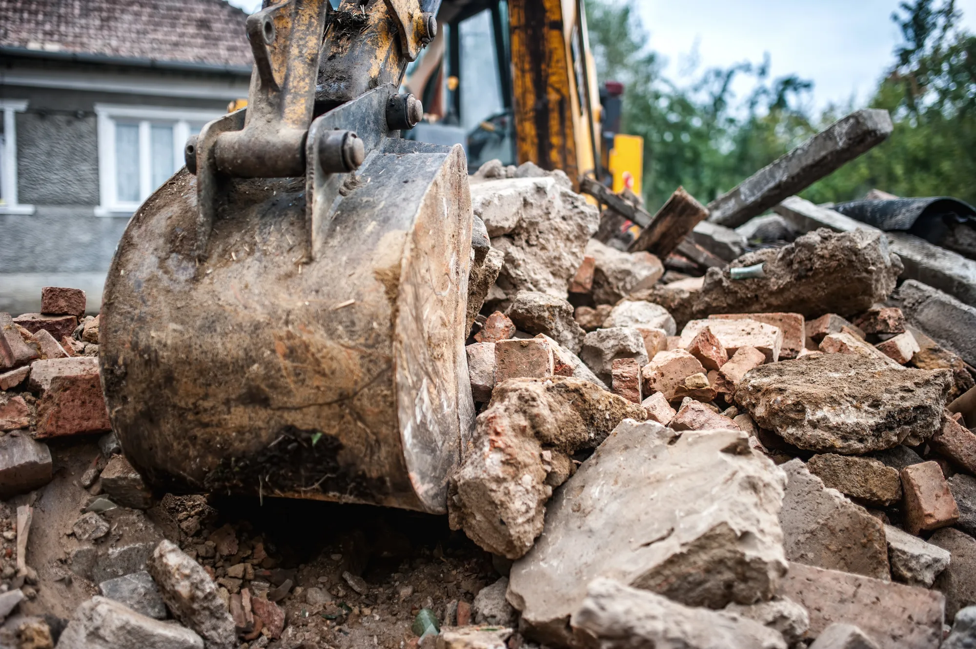 Excavator bucket lifting brick rubble from a demolition site