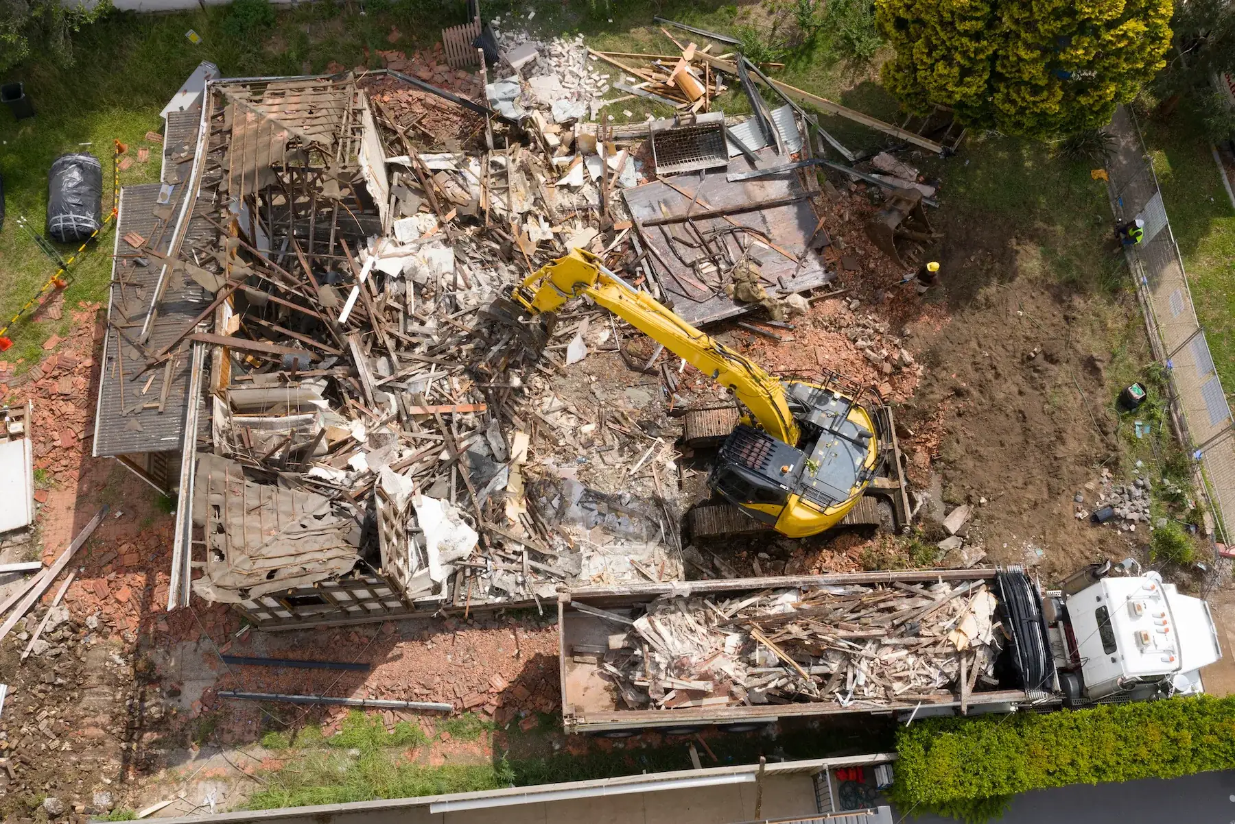 Aerial view of a house demolition with excavator and truck