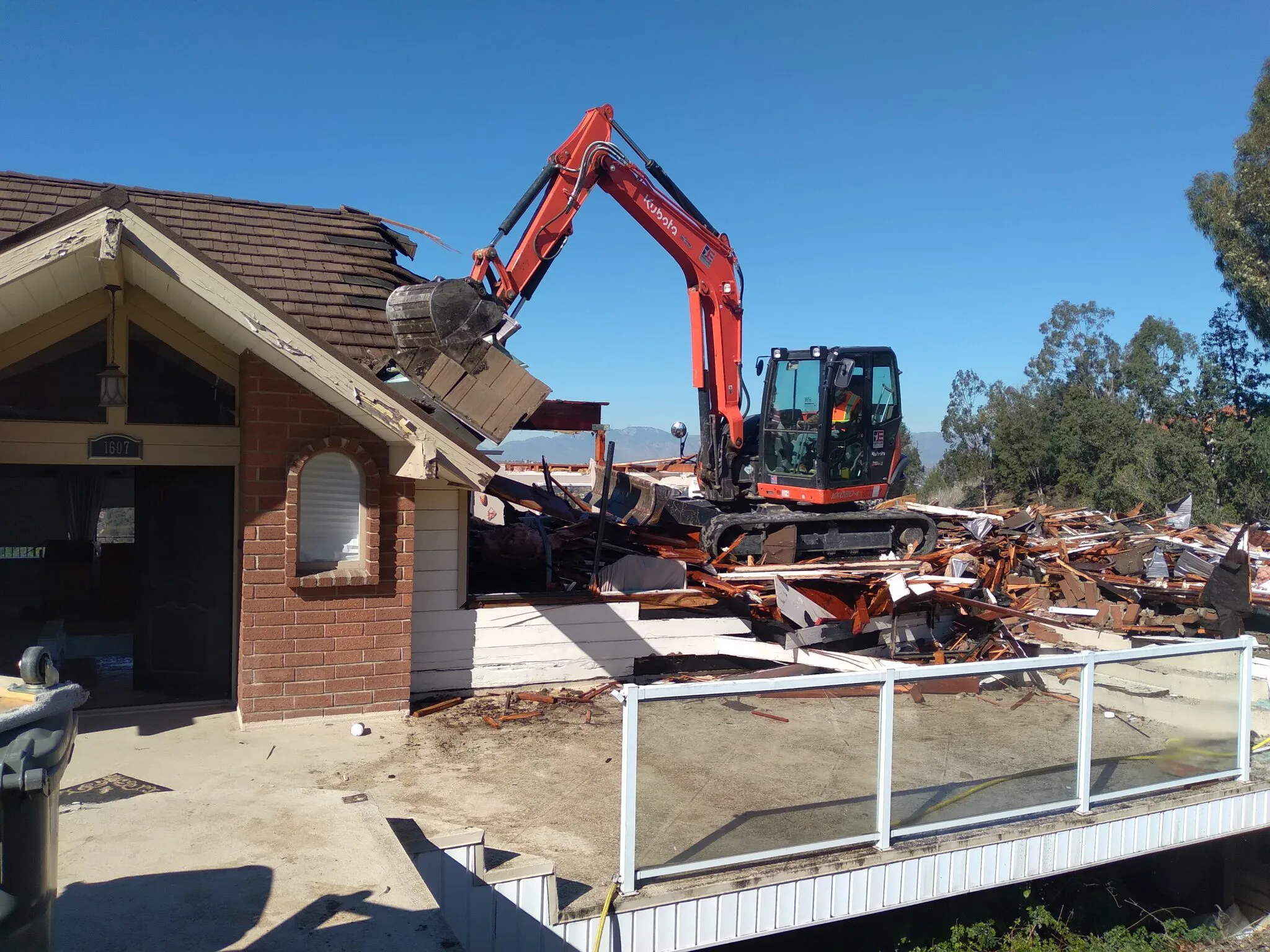 Excavator demolishing a brick residential building